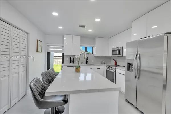 a kitchen with refrigerator and chairs