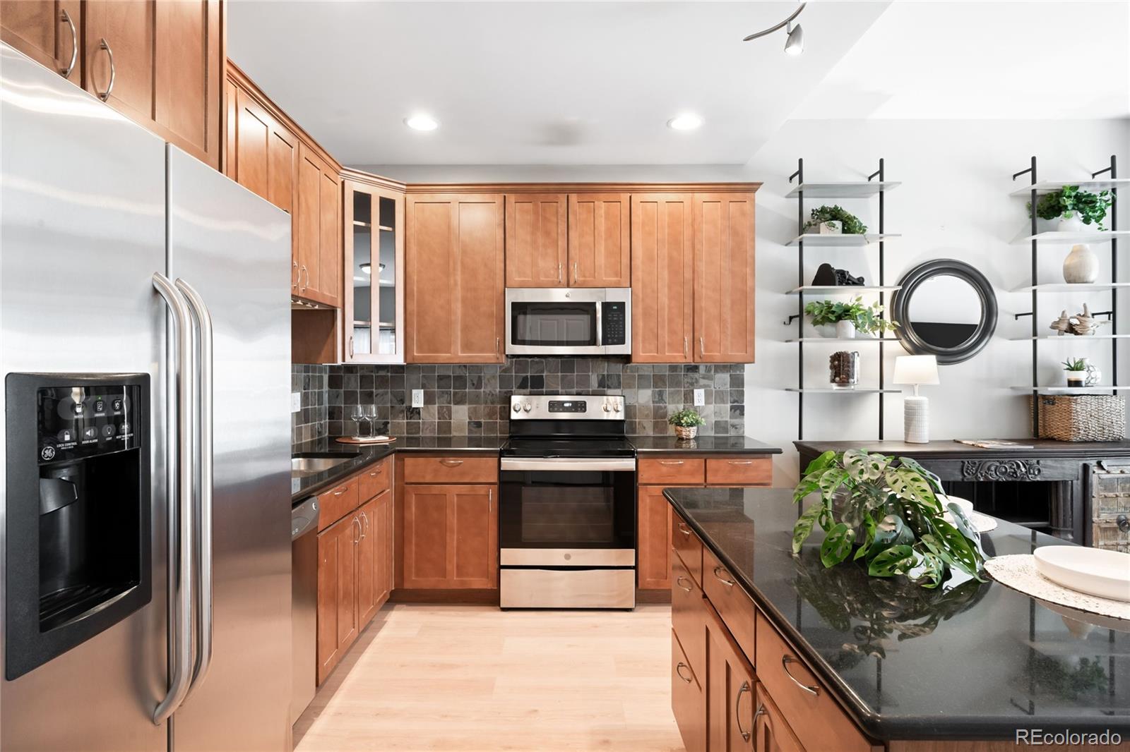 1950 Logan Street, Unit 901 Denver, CO 80203 - Photo 4 of 24 a kitchen with stainless steel appliances granite countertop a stove a sink and a refrigerator