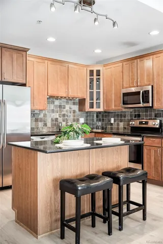 a kitchen with stainless steel appliances granite countertop a stove top oven a sink with dining table and chairs