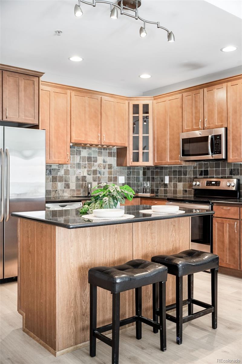 1950 Logan Street, Unit 901 Denver, CO 80203 - Photo 5 of 24 a kitchen with stainless steel appliances granite countertop a stove top oven a sink with dining table and chairs