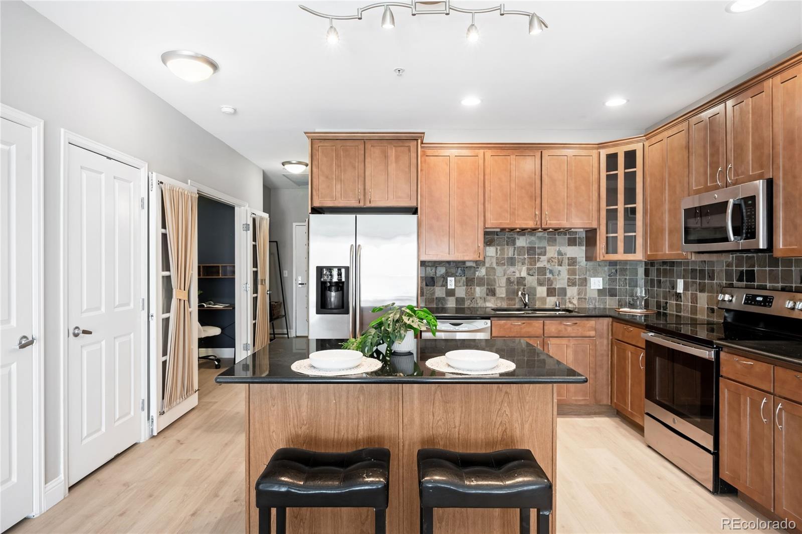 1950 Logan Street, Unit 901 Denver, CO 80203 - Photo 6 of 24 a kitchen with stainless steel appliances granite countertop a stove top oven a sink dishwasher a dining table and chairs with wooden floor