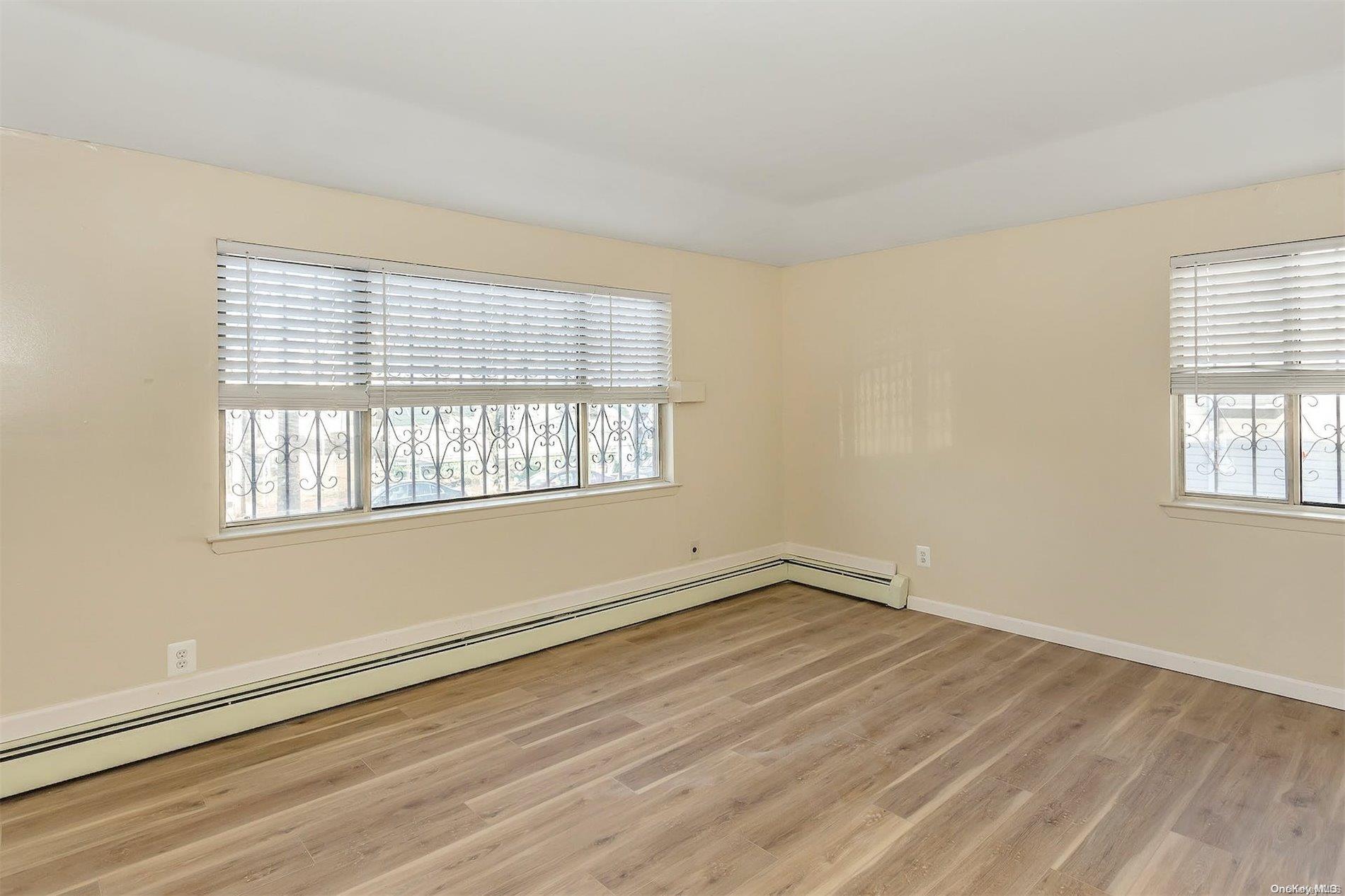 165-28 144th Drive Queens, NY 11434 - Photo 14 of 25 a view of an empty room with wooden floor and a window