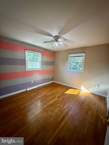 a view of an empty room with window and chandelier fan