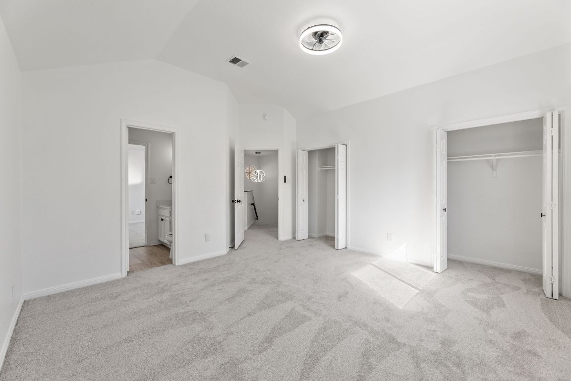 2127 Redwing Way Round Rock, TX 78664 - Photo 18 of 33 bedroom featuring multiple closets, lofted ceiling, light carpet, and ensuite bath