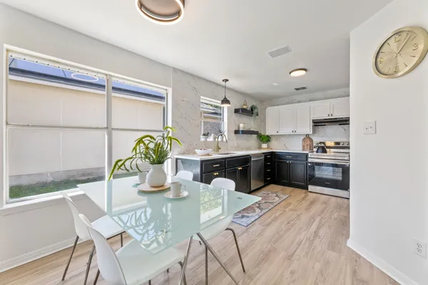 a kitchen with stainless steel appliances kitchen island granite countertop a sink a stove a dining table and chairs