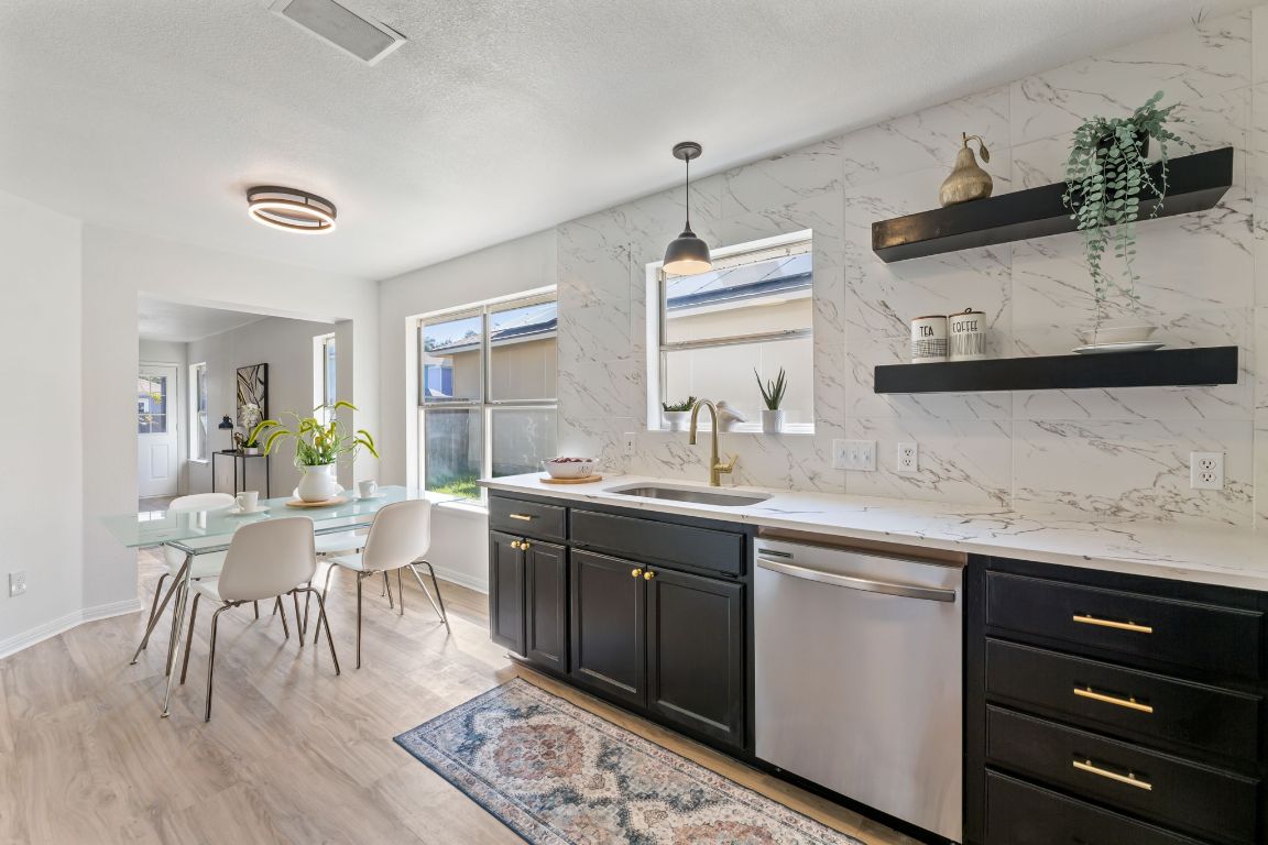2127 Redwing Way Round Rock, TX 78664 - Photo 9 of 33 Kitchen featuring dark cabinets, decorative backsplash, dishwasher, light stone countertops, and pendant lighting