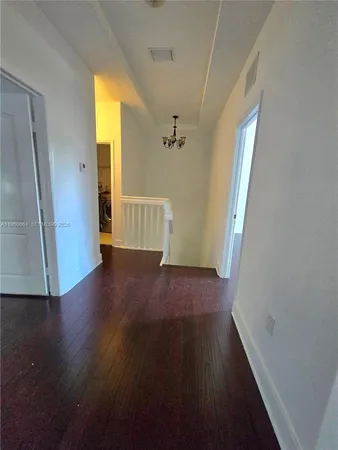 a view of a hallway view with wooden floor and a cabinet