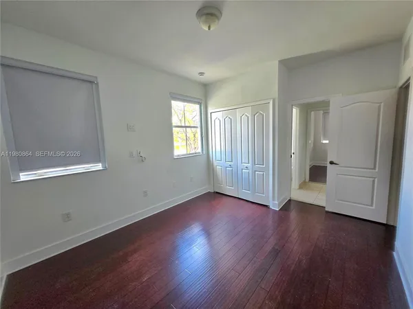 an empty room with wooden floor and windows