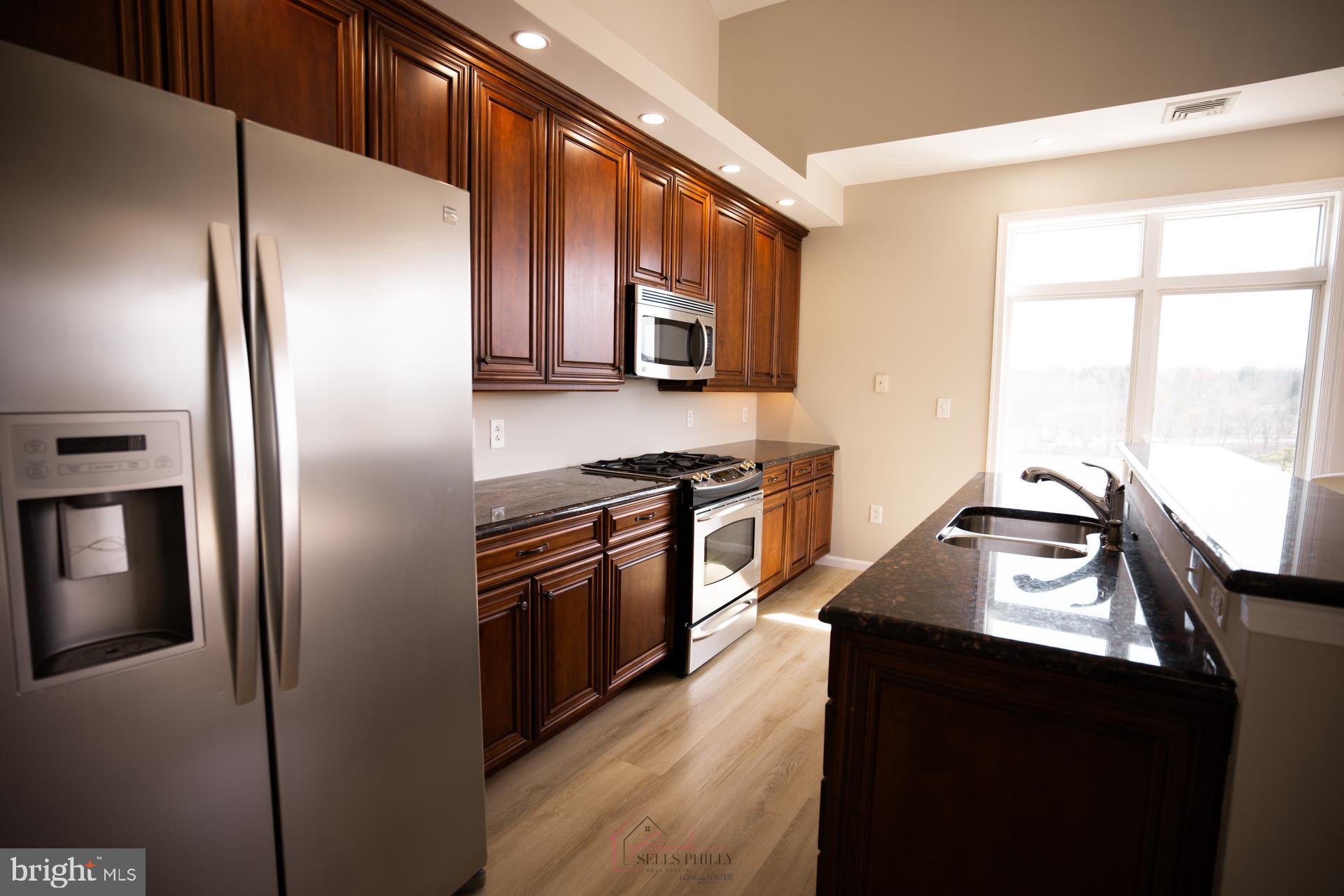528 Carson Terrace Huntingdon Valley, PA 19006 - Photo 17 of 43 a kitchen with stainless steel appliances granite countertop a refrigerator a stove and a sink with wooden floor