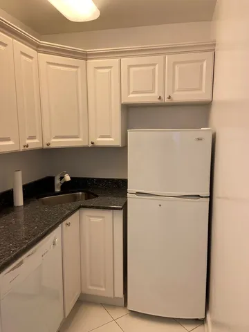 a kitchen with granite countertop white cabinets and white appliances