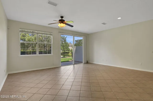 an empty room with a ceiling fan and window