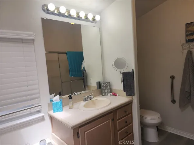 a bathroom with a sink vanity granite toilet and a mirror
