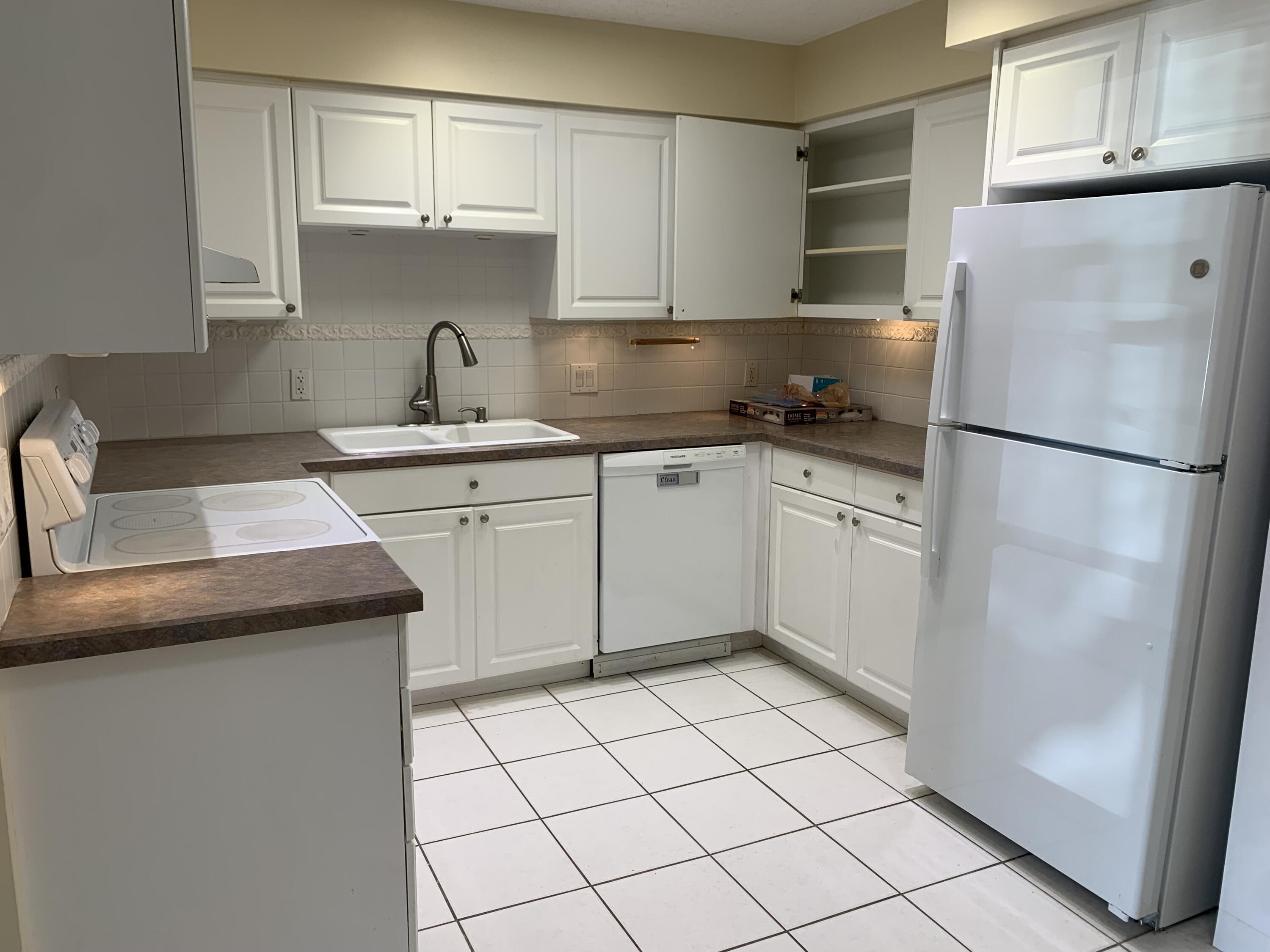 2822 Duke Lane Delray Beach, FL 33445 - Photo 4 of 12 a kitchen with a sink a refrigerator and cabinets