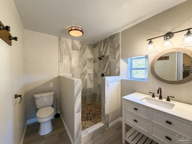 a bathroom with a toilet sink vanity granite and a mirror