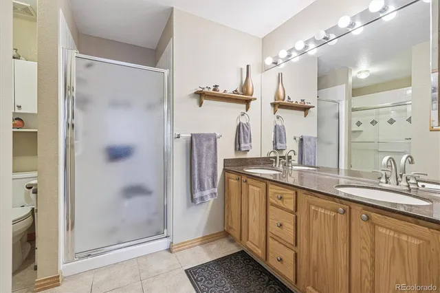 a spacious bathroom with a double vanity sink a mirror and a shower