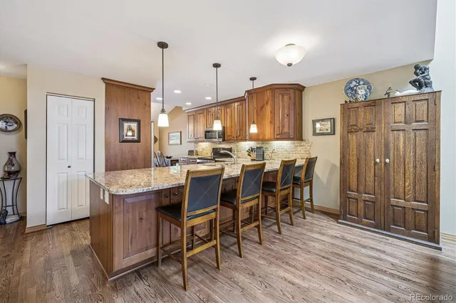 a kitchen with stainless steel appliances granite countertop wooden floors and wooden cabinets