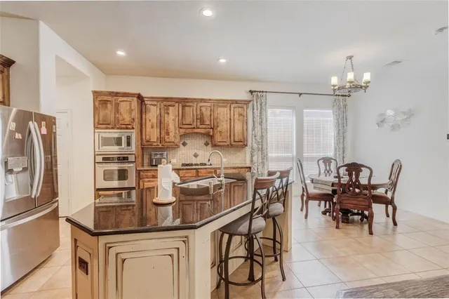 a kitchen with stainless steel appliances granite countertop a table and chairs