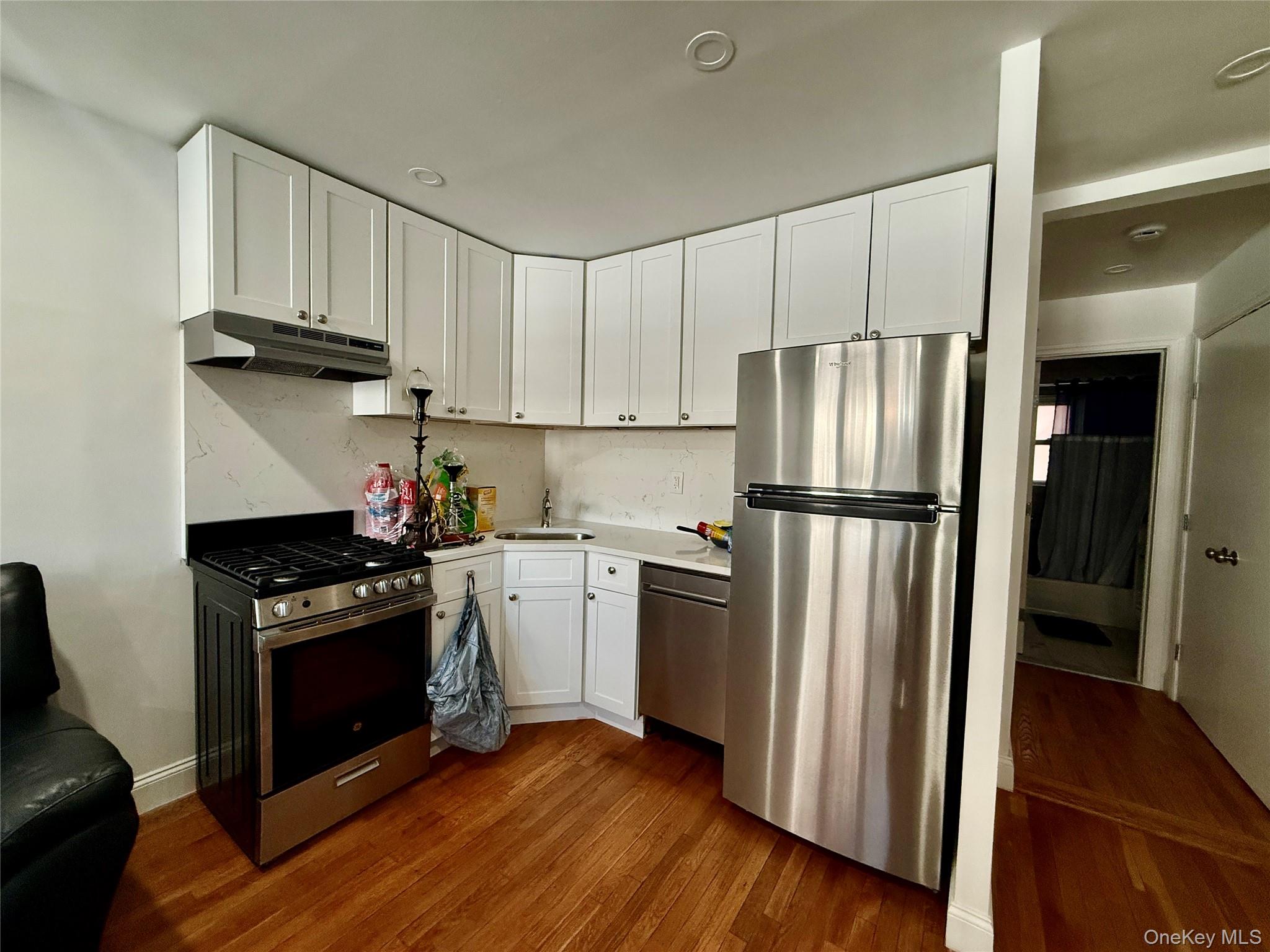 765 Shore Road, Unit 1N Long Beach, NY 11561 - Photo 6 of 13 a kitchen with granite countertop a refrigerator stove and wooden floor