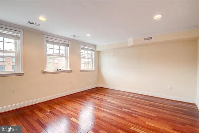 an empty room with wooden floor and windows