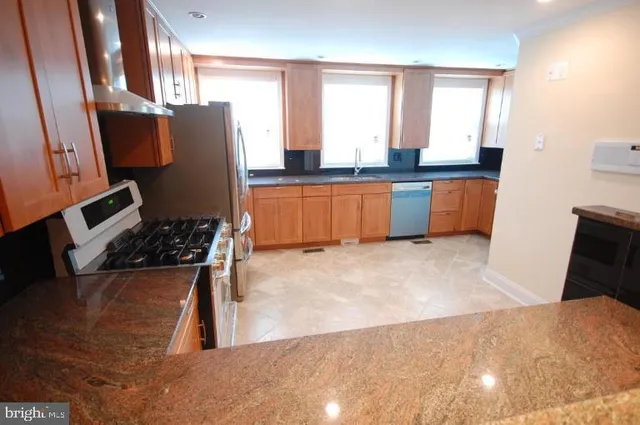 a kitchen with stainless steel appliances a refrigerator a sink a stove and cabinets
