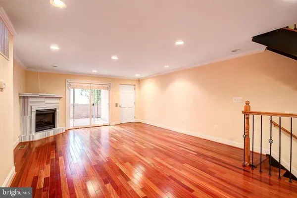 a view of an empty room with wooden floor fireplace and a window