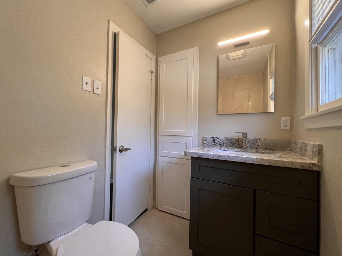 5834 Indigo Street Houston, TX 77074 - Photo 11 of 15 a bathroom with a granite countertop toilet sink and mirror