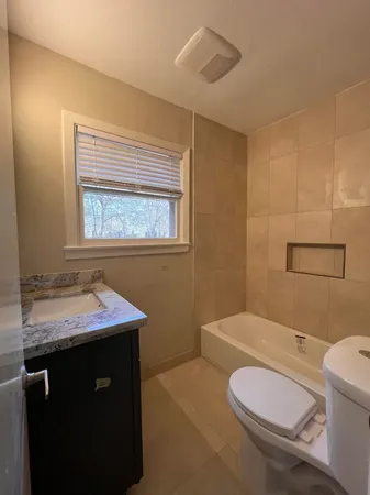 a bathroom with a granite countertop toilet sink and mirror