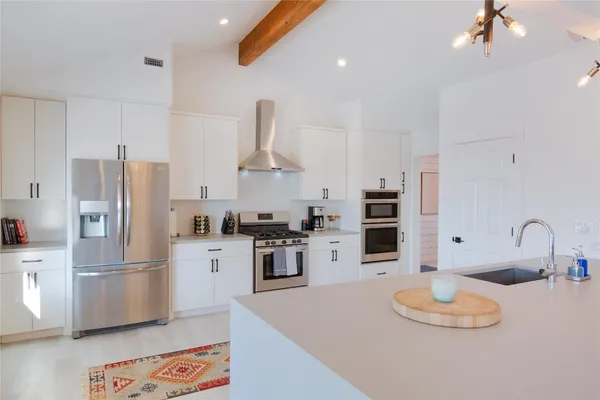 a kitchen with stainless steel appliances granite countertop a sink a stove and a refrigerator