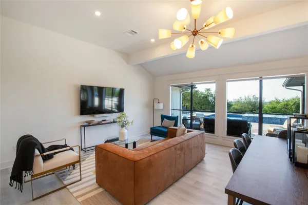 a living room with furniture a flat screen tv and a large window