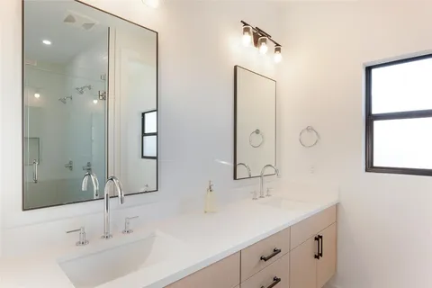 a bathroom with a double vanity sink mirror and next to a window