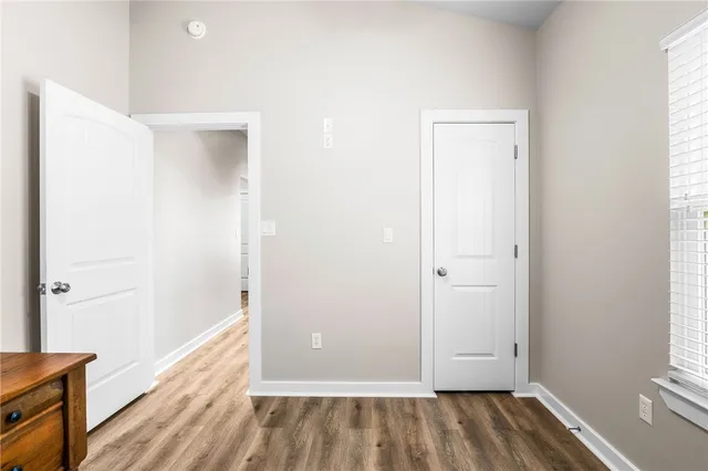 a view of a hallway with wooden floor and a bathroom