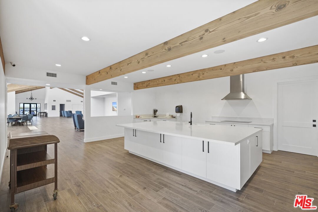 29500 Heathercliff Road, Unit 252 Malibu, CA 90265 - Photo 46 of 50 a large white kitchen with wooden floors and stainless steel appliances