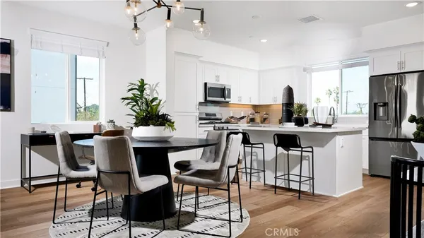 a kitchen with stainless steel appliances kitchen island a table chairs in it and white cabinets