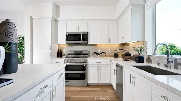 a kitchen with white cabinets and appliances