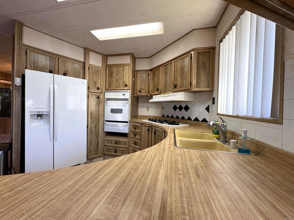 7467 Mission Gorge Road, Unit 293 Santee, CA 92071 - Photo 4 of 49 a kitchen with granite countertop a refrigerator stove top oven and sink