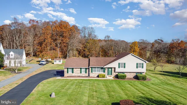 a view of a house with yard and trees in the background