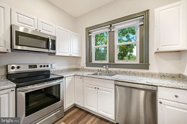 a kitchen with granite countertop a stove a sink and a microwave