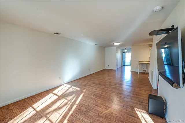 a view of empty room with wooden floor and a window