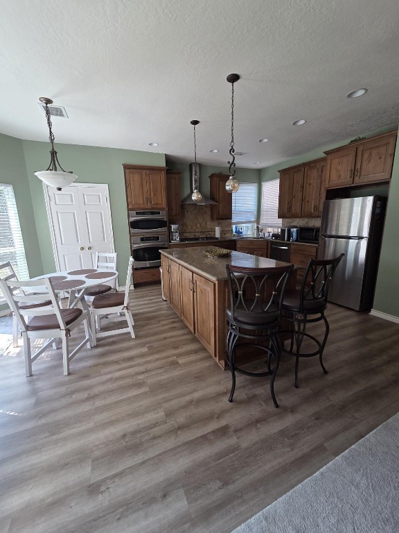 1203 Cardinal Lane Round Rock, TX 78681 - Photo 5 of 17 a kitchen with stainless steel appliances granite countertop a stove top oven a refrigerator a dining table and chairs with wooden floor