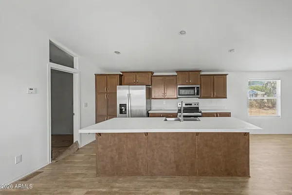 a large white kitchen with kitchen island a sink wooden floor and a refrigerator