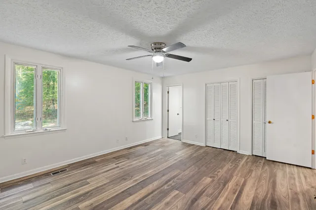 a view of empty room with wooden floor and fan