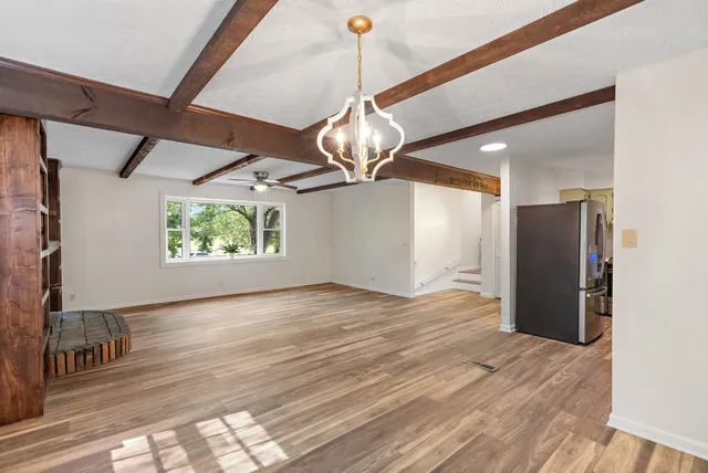 a view of an empty room with wooden floor and windows