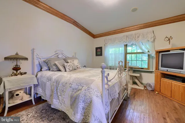 a bedroom with a bed and a flat tv screen on dresser
