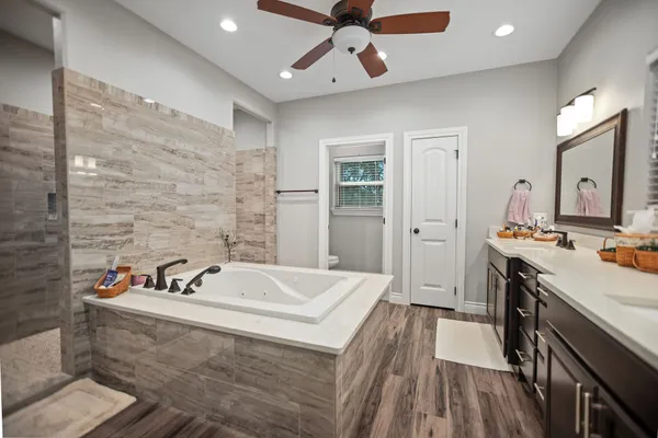 a large spacious bathroom with a tub sink shower and mirror