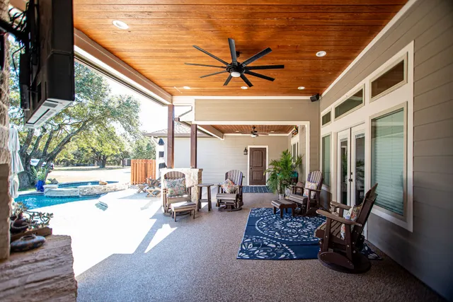 a view of a patio with table and chairs potted plants and floor to ceiling window