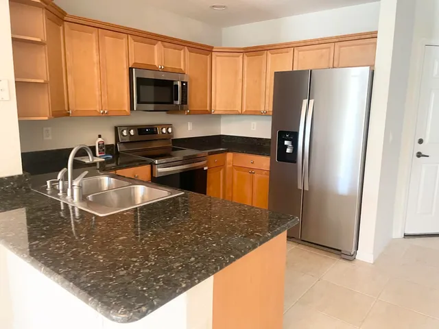 a kitchen with stainless steel appliances granite countertop a refrigerator a stove top oven a sink and dishwasher