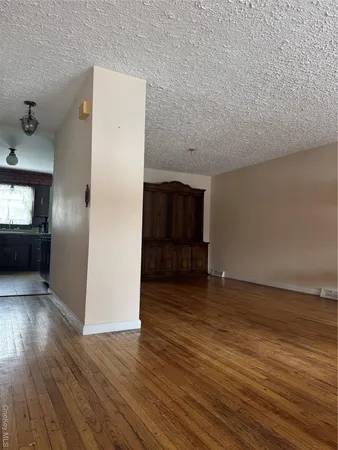 an empty room with wooden floor cabinet and windows