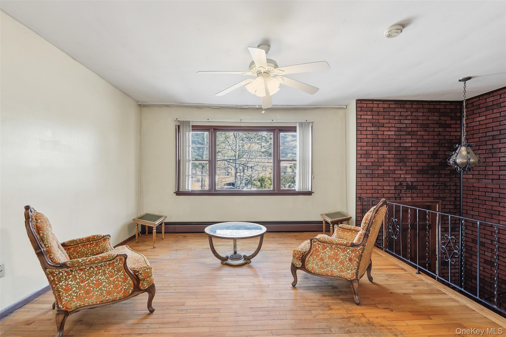 563 Union Road Spring Valley, NY 10977 - Photo 5 of 16 Expansive room featuring wood-finish flooring, a red brick accent wall, and a multi-pane window