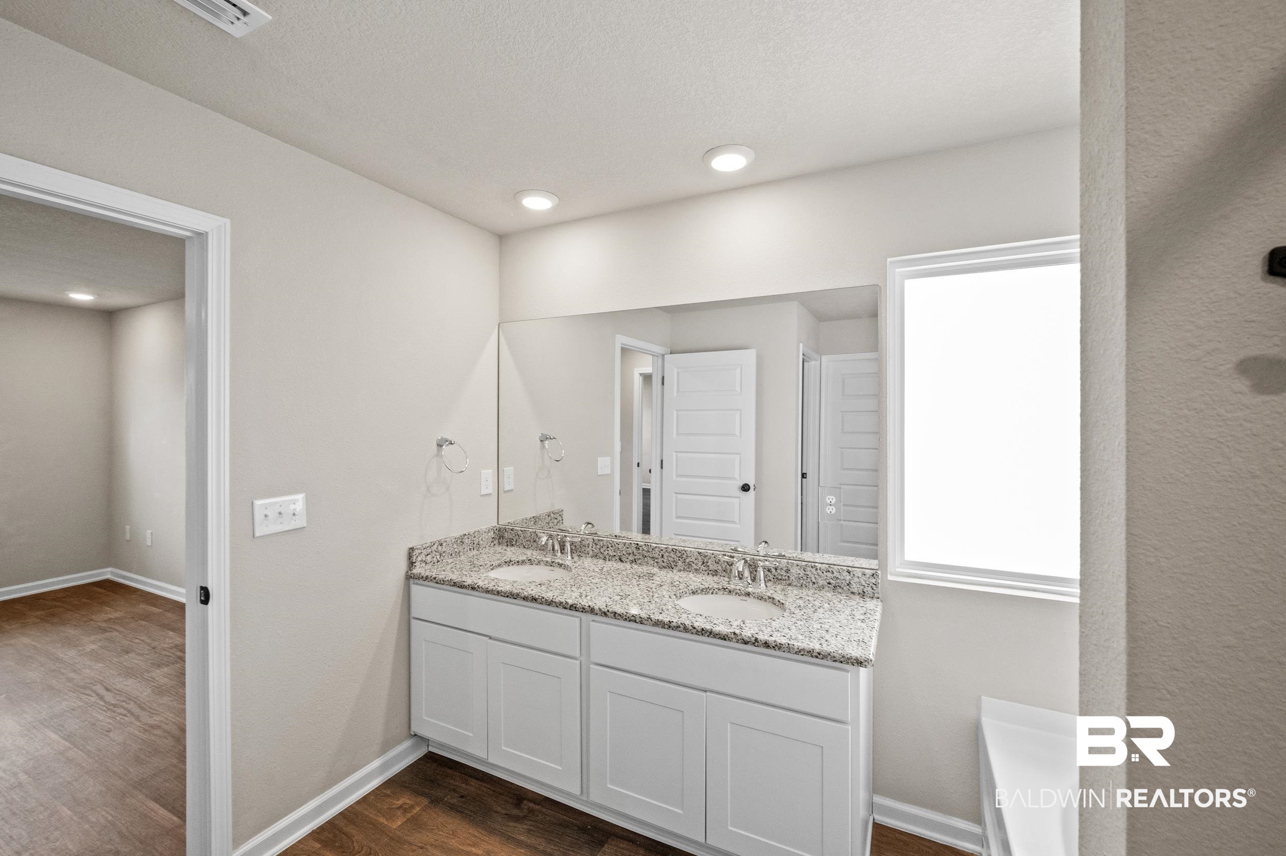 10353 Zenyatta Loop Daphne, AL 36526 - Photo 18 of 33 Bathroom featuring double sink vanity, a tub, and hardwood / wood-style floors