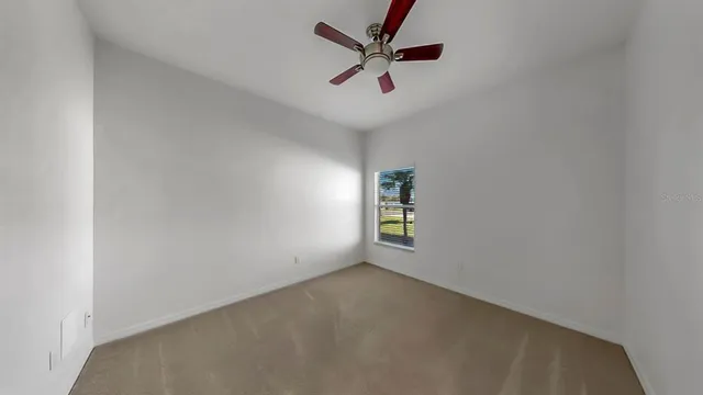 an empty room with a window and ceiling fan
